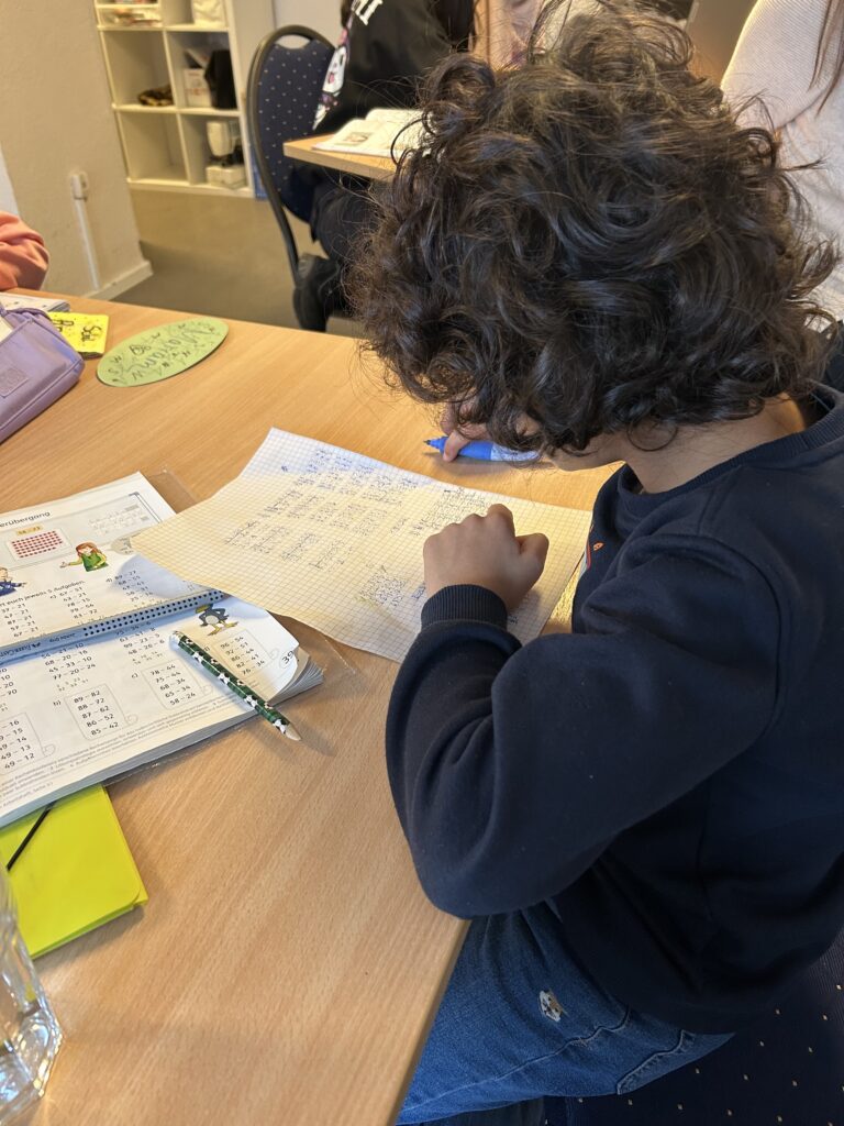 Kind sitzt am Tisch und schreibt
